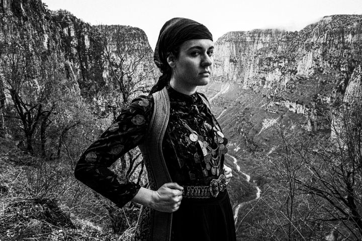 A woman wearing the local costume of Zagori, standing before the Vikos gorge