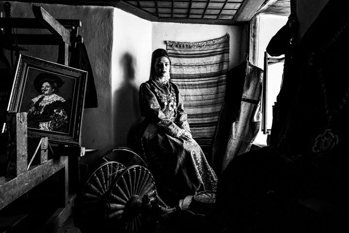 Woman sitting inside a local traditional mansion, wearing the local urban costume of Kastoria.