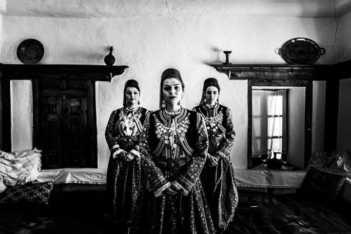 Woman sitting inside a local traditional mansion, wearing the local urban costume of Kastoria.