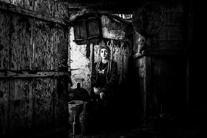 A woman wearing the rural costume of Kastoria inside a local house in the village of Lefki. Chiaroscuro portrait