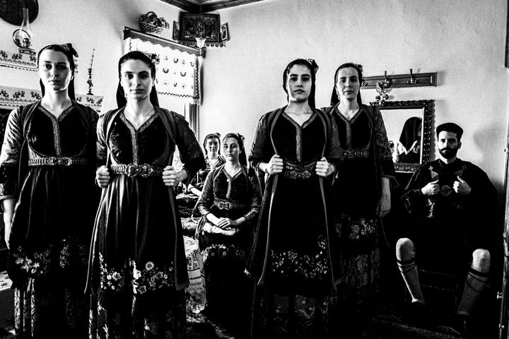 A group of people wearing the traditional costumes of Metsovo, Epirus, inside a local house.