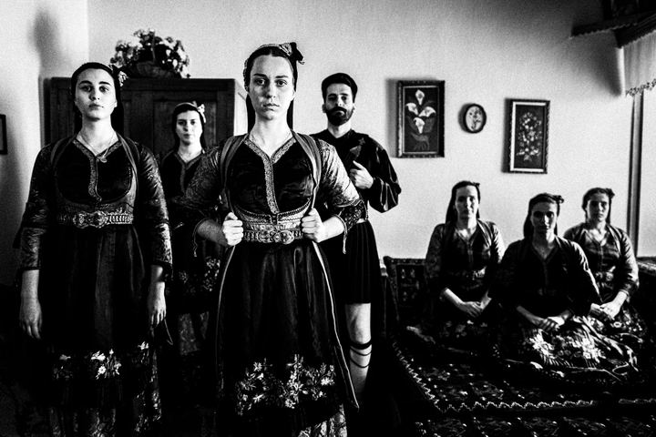 A group of people wearing the traditional costumes of Metsovo, Epirus, inside a local house.