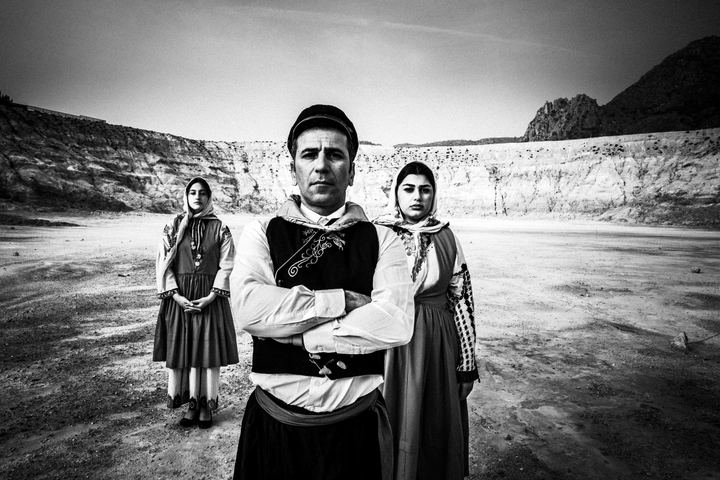 Two women and a man, wearing the local costumes of Nisyros, standing inside the crater of the island's volcano