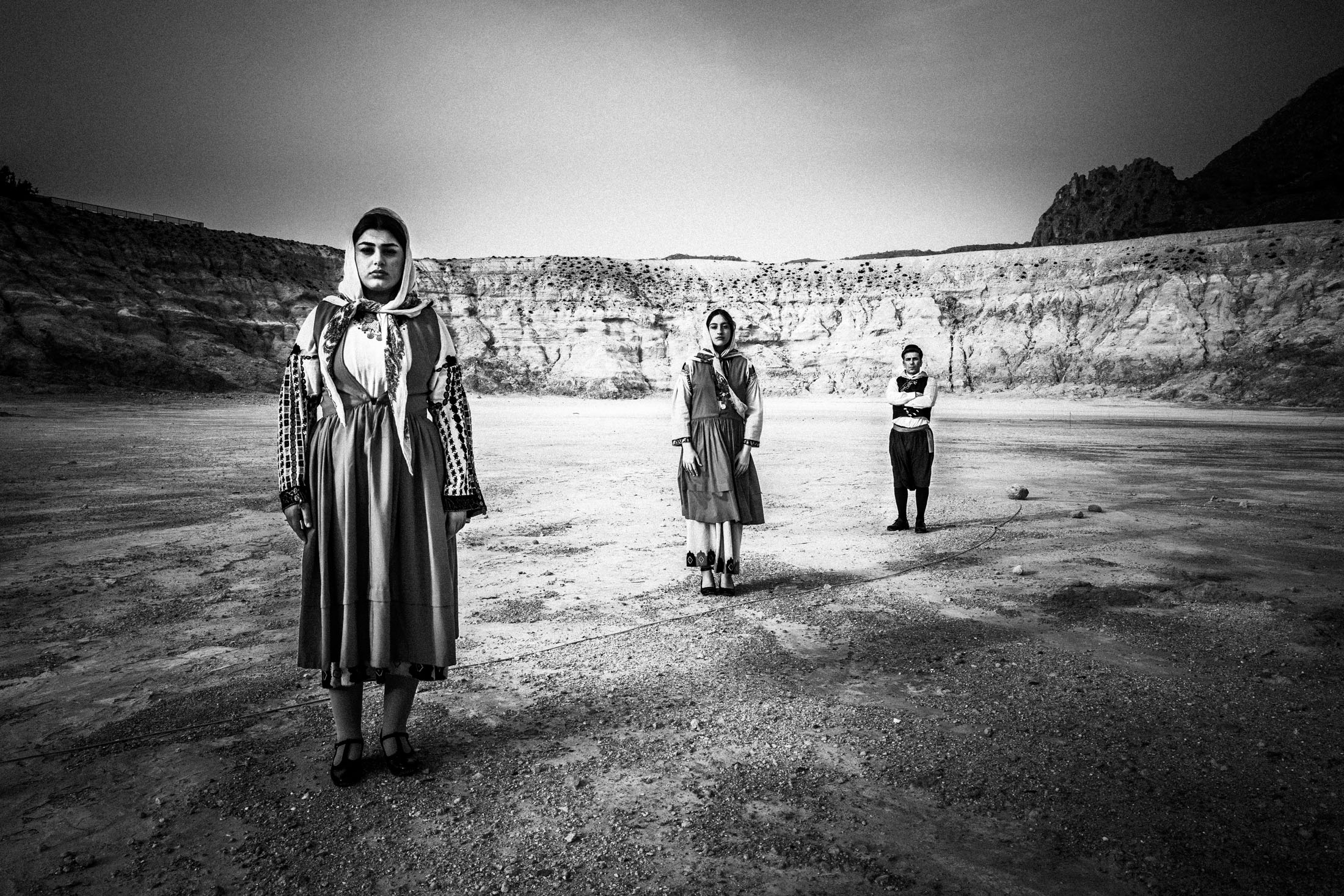 Two women and a man, wearing the local costumes of Nisyros, standing inside the crater of the island's volcano