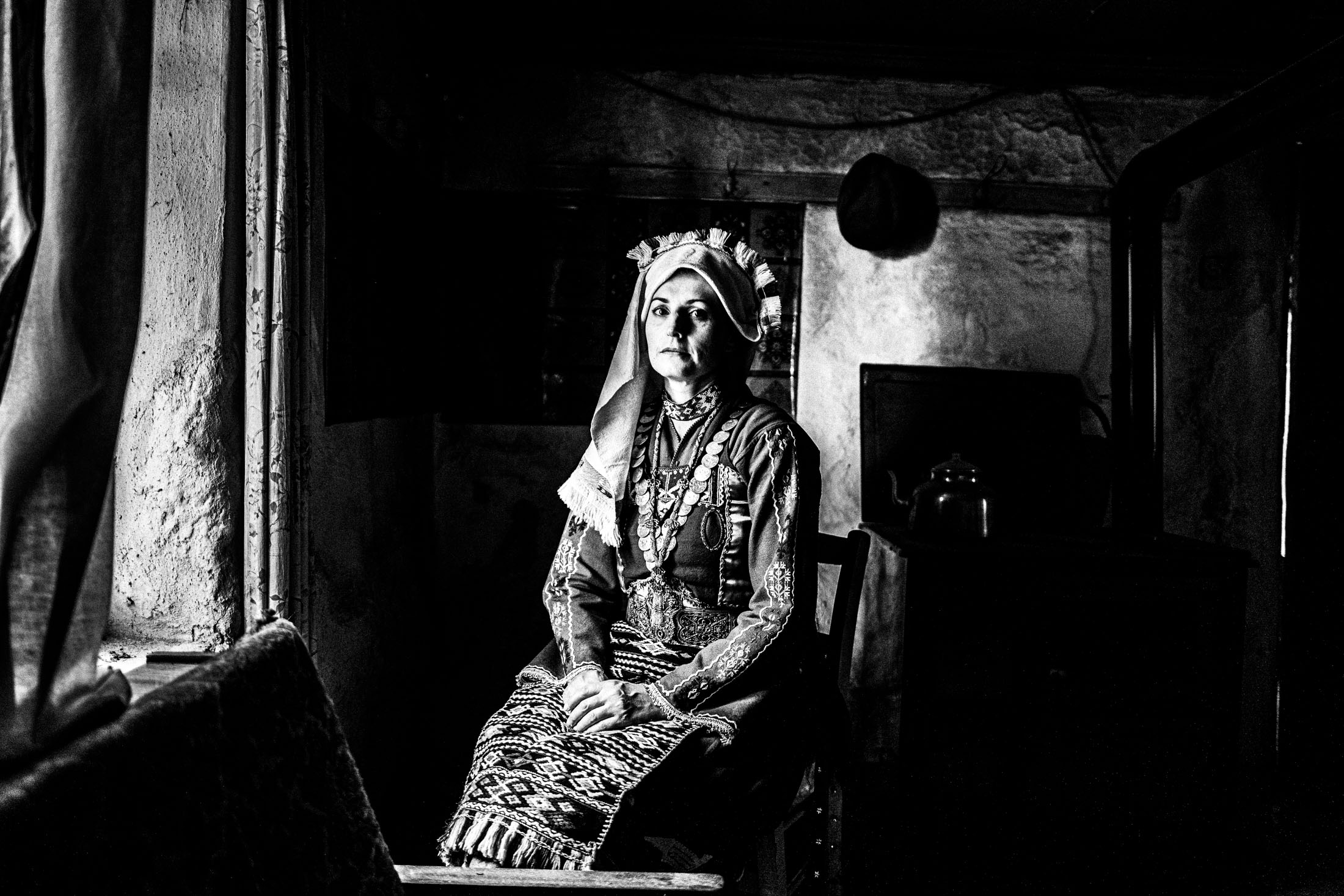 Woman wearing the local costume of Mani, Evros, sitting by a window in a local house