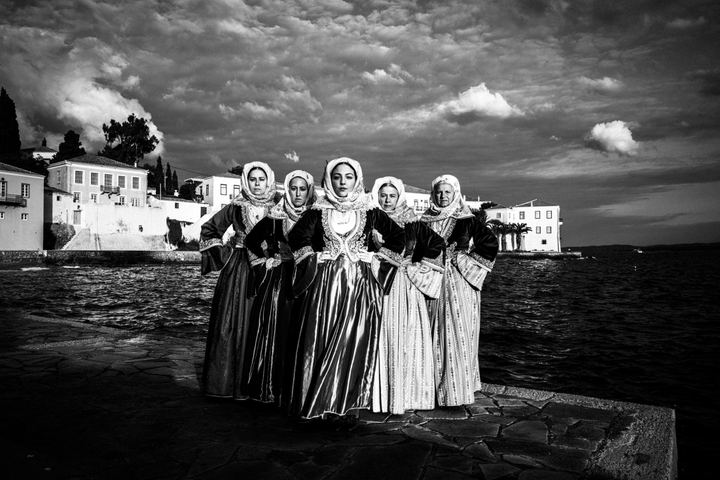 Women wearing the local costumes of Spetses, standing on a pier on the island
