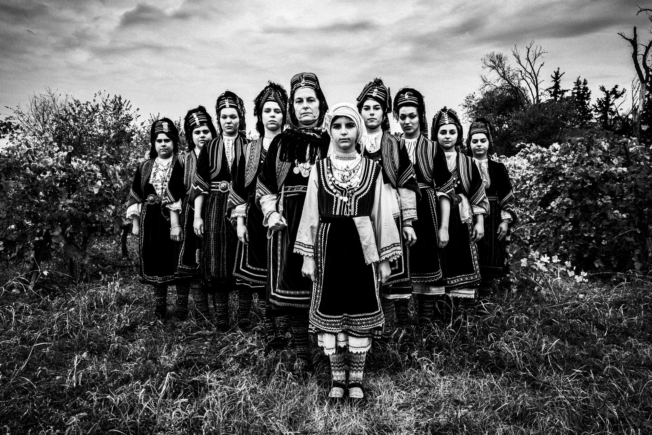 A group of women wearing the local costumes of Prosotsani, Drama standing in formation at a local vineyard