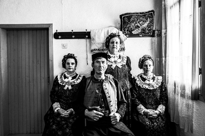 A family of four wearing the local costumes of Nea Vyssa in Evros, posing for a traditional portrait inside a local house by the window