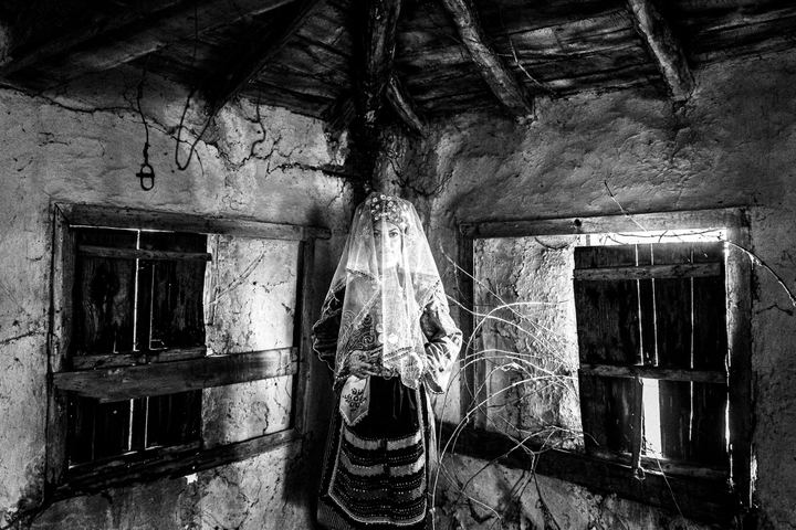A veiled woman wearing the local bridal dress of Metaxades, inside a local house. Evros, Thrace