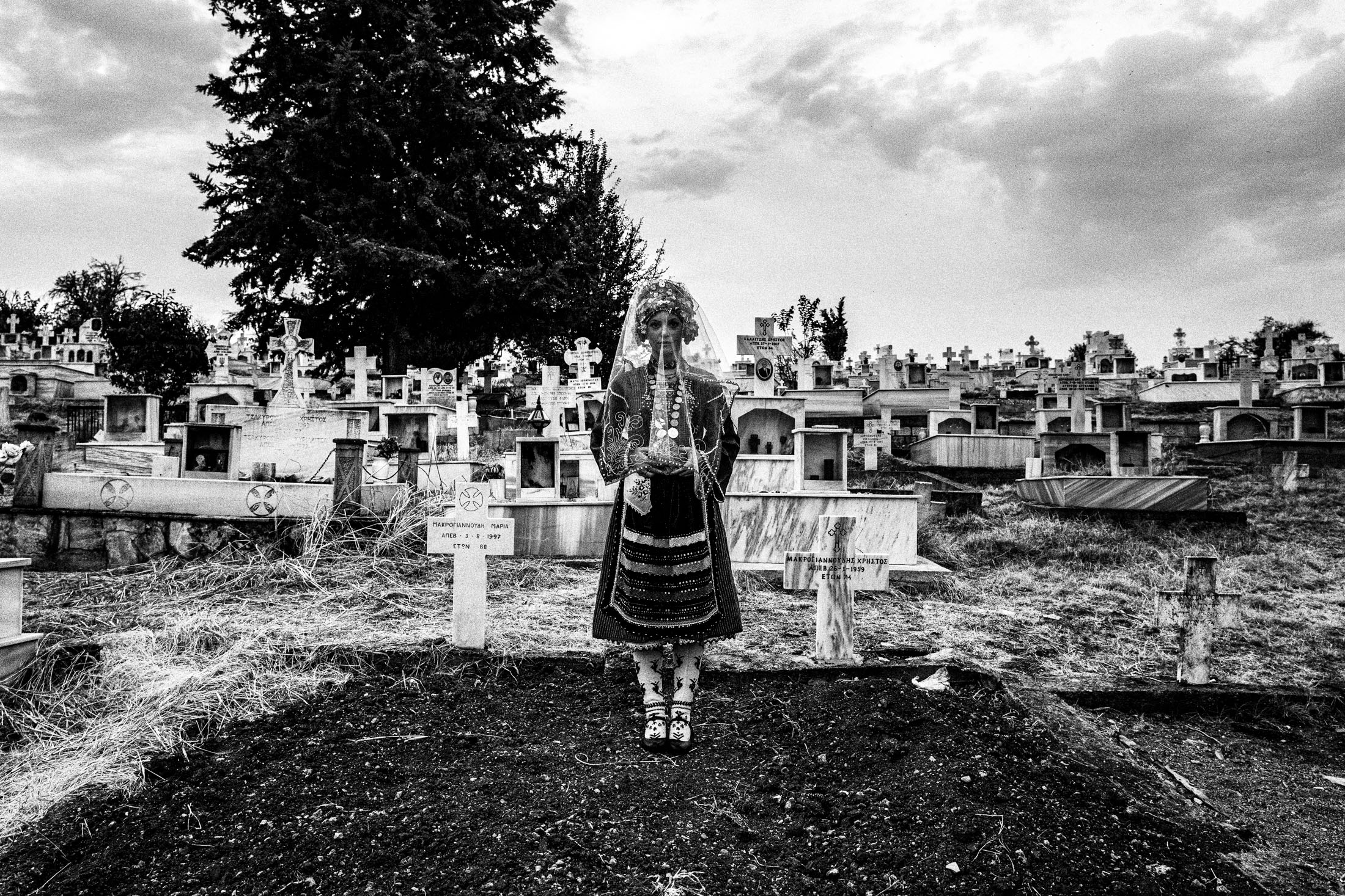 A veiled woman wearing the local bridal dress of Metaxades, at the local cemetery. Evros, Thrace