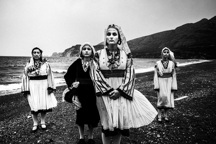 Four women wearing the local costumes of Tilos, stand at the beach of Eristos on the island