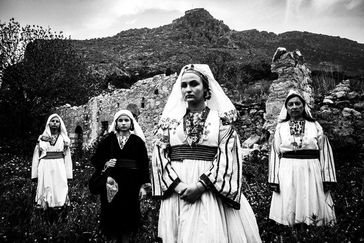 Four women wearing the local costumes of Tilos, stand by the fortyfying walls of Megalo chorio on the island.