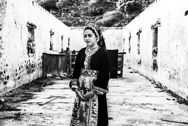 A young woman wearing the local Kavathe costume of Olympos Karpathos, posing inside a ruined house in Tristormo, Karpathos