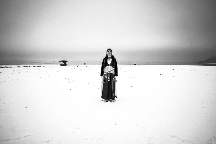 Ourania wearing the traditional Pontic costume in lake Kerkini. The lake is frozen and there is a wooden boat behind the woman.