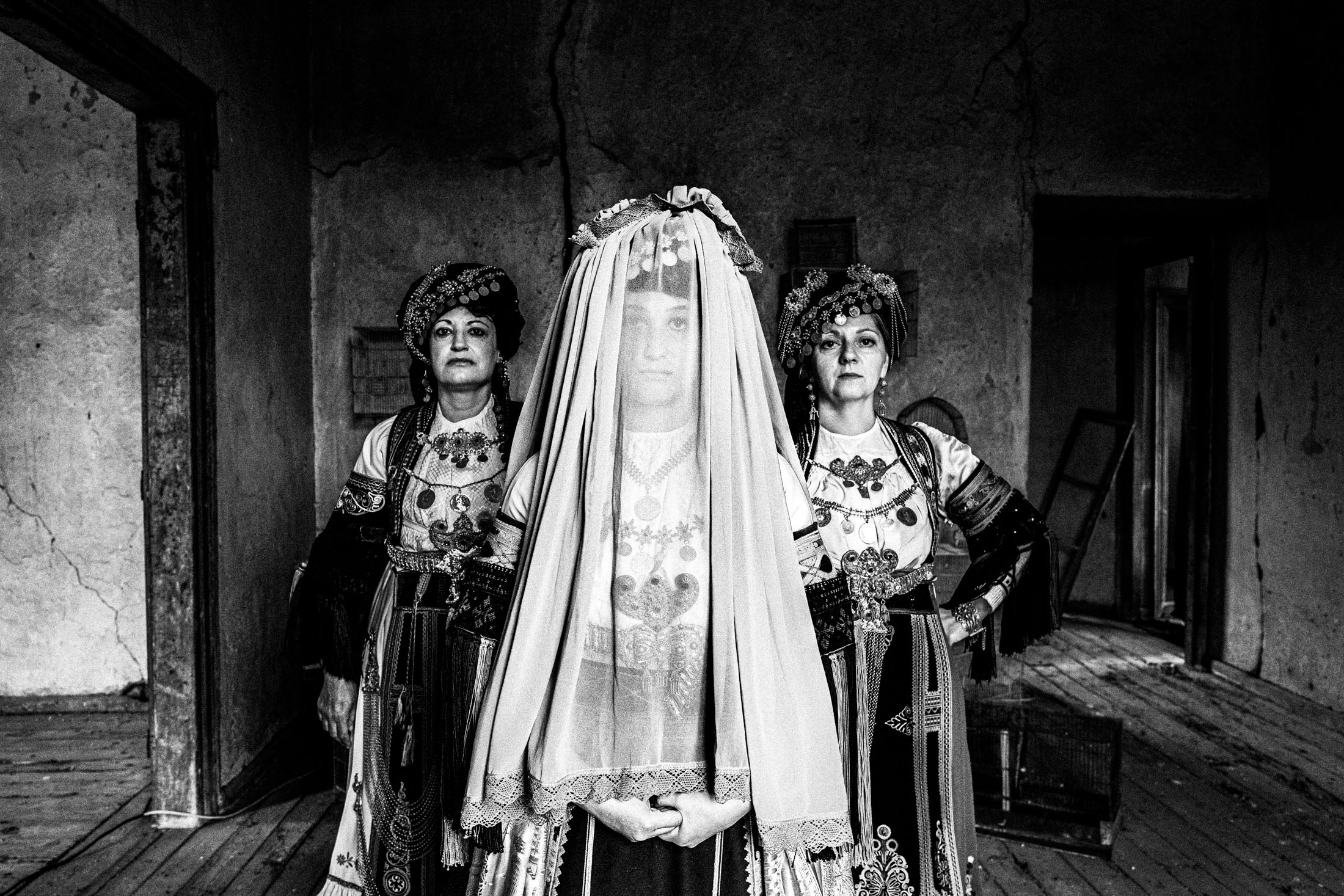 Three women wearing the Karagouna costumes, inside a local mansion in Glinos. The woman in the front wears the veiled bridal dress