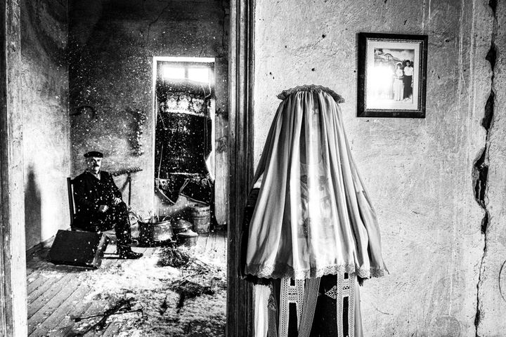 A veiled woman wearing the Karagouna bridal dress and a man in a traditional three-piece suit, inside a local mansion in Glinos, Trikala