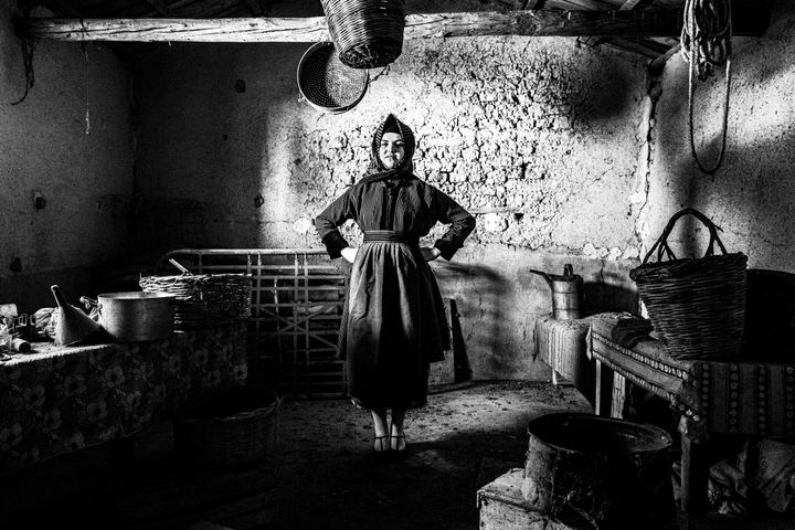 A woman wearing the local dress of Stafanovikio, standing inside an old local warehouse