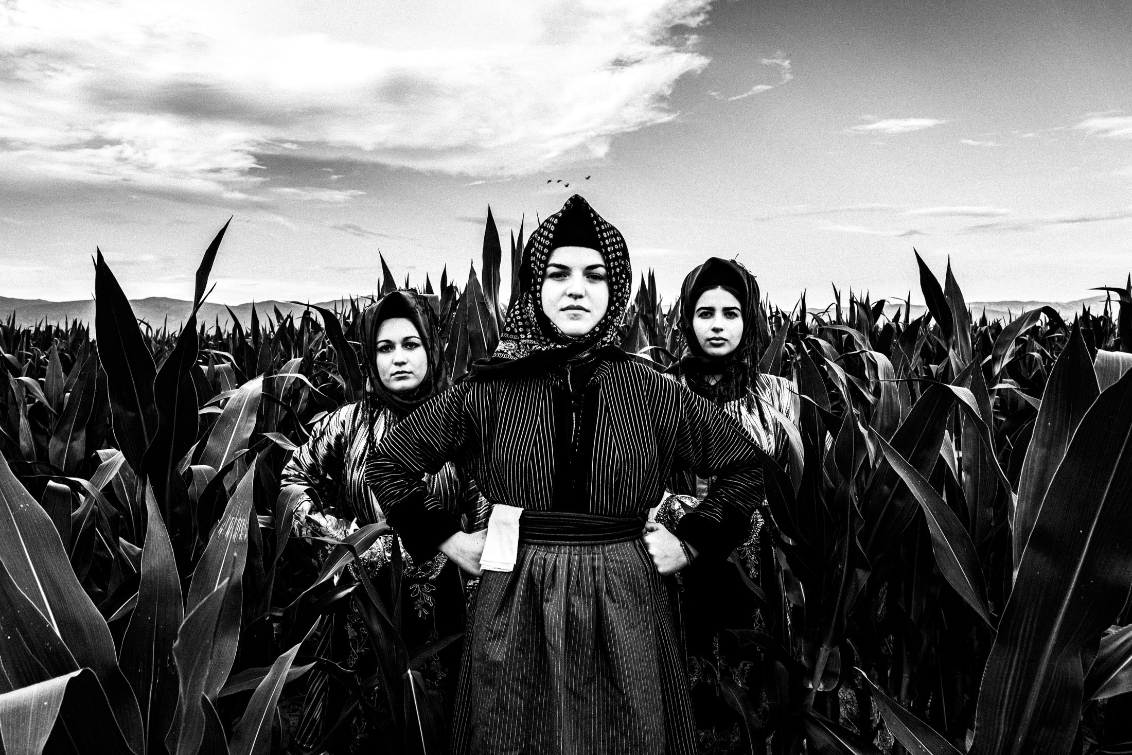 Three women wearing the local costumes of Stefanovikio in Thessaly, standing in a local field