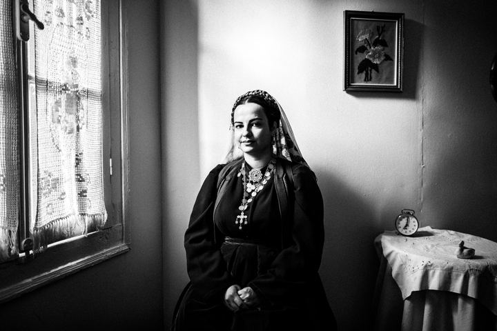 A woman wearing the local dress of Platanos, Nafpaktia, inside a local house by the window