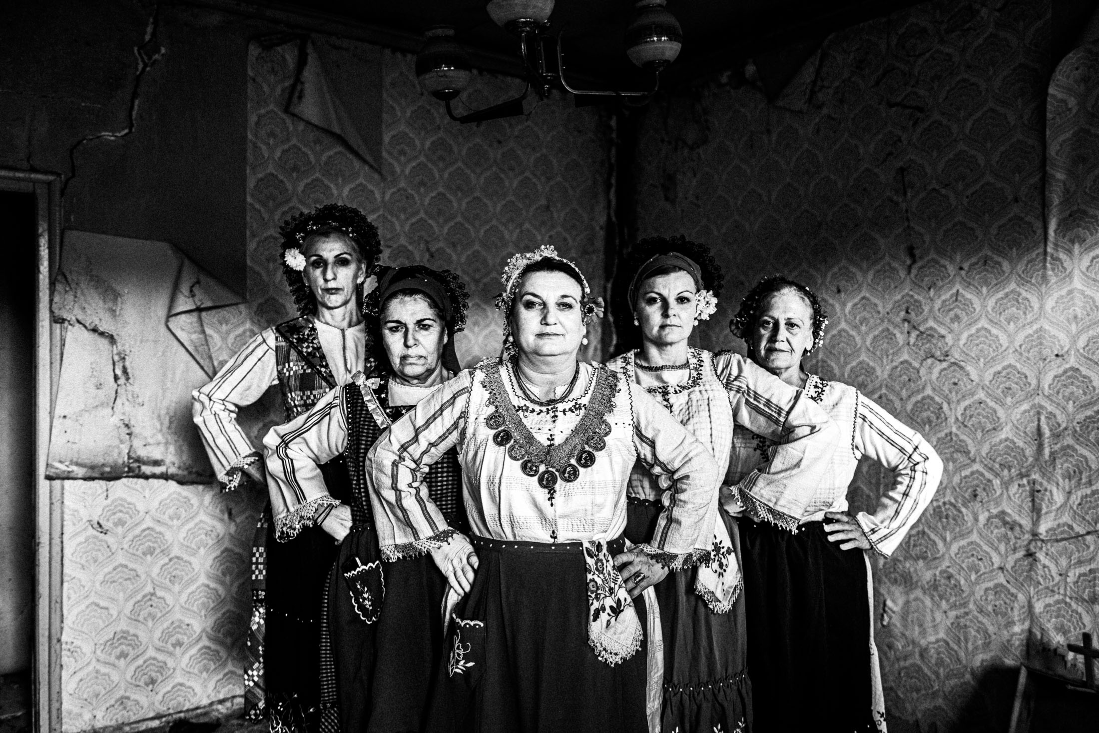 Five women wearing the local costumes of Enoe in Orestiada, standing in formation inside an old local house.