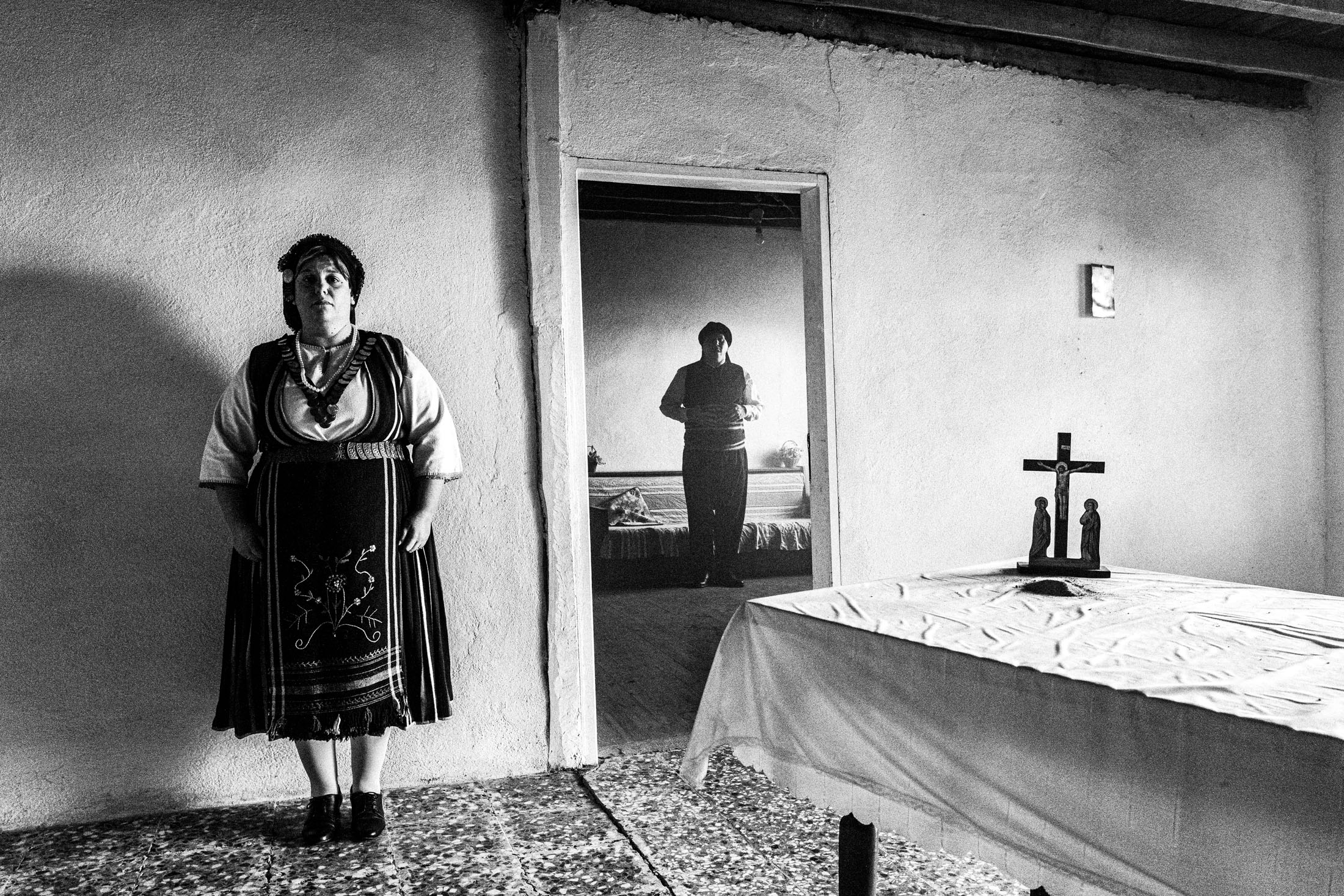 A woman and a man dressed in the traditional costumes of Eastern Romylia, inside an old house in Mani, Evros