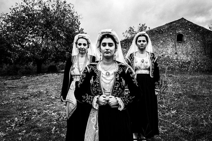 Three women in the costumes of Northern Corfu posing at a local field