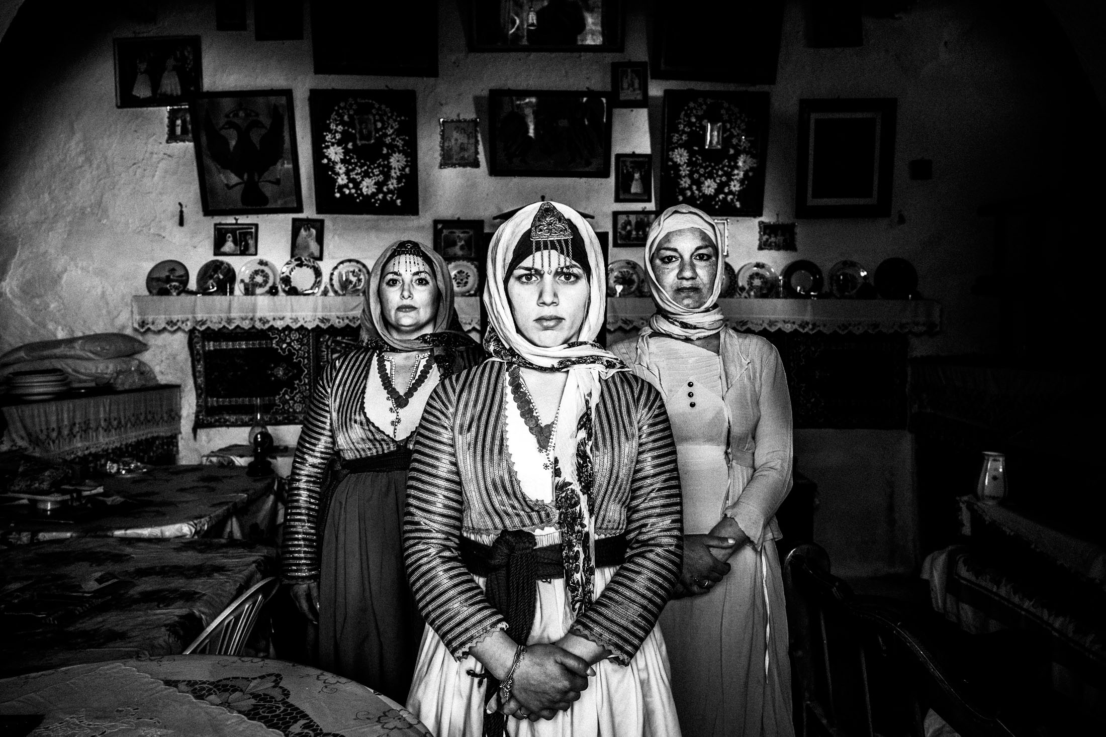 Three women wearing the costumes of Gennadi, Rhodes, stand inside a local house