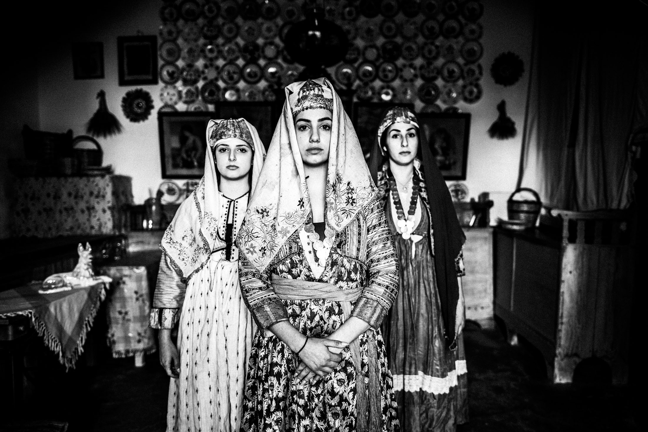 Three women wearing the local costumes of Archangelos in Rhodes, standing inside a local traditional house