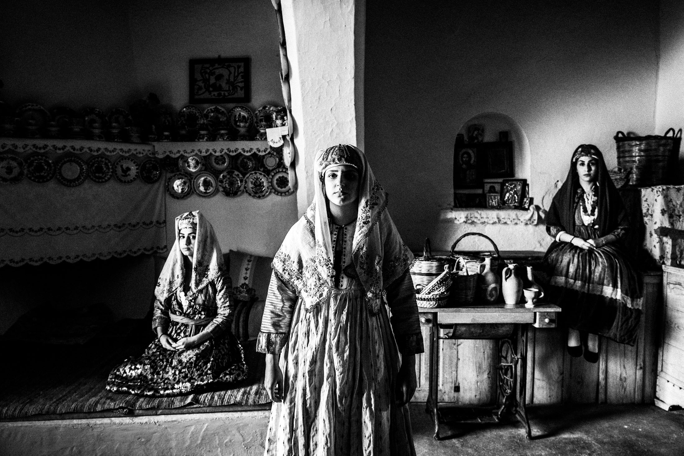 Three women wearing the local costumes of Archangelos in Rhodes, standing inside a local traditional house