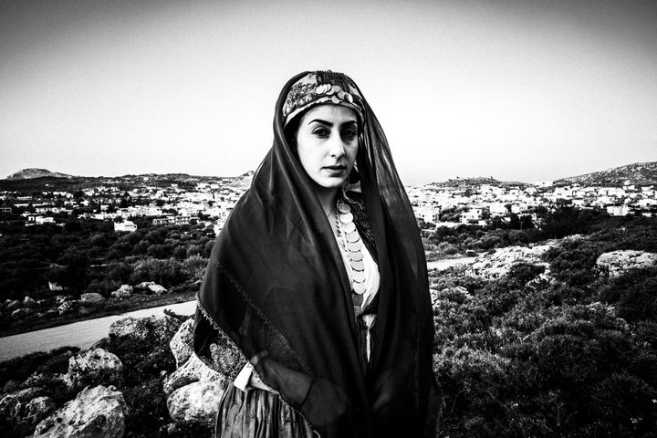 A woman wearing the costume of Archangelos, standing outdoors, overlooking the village