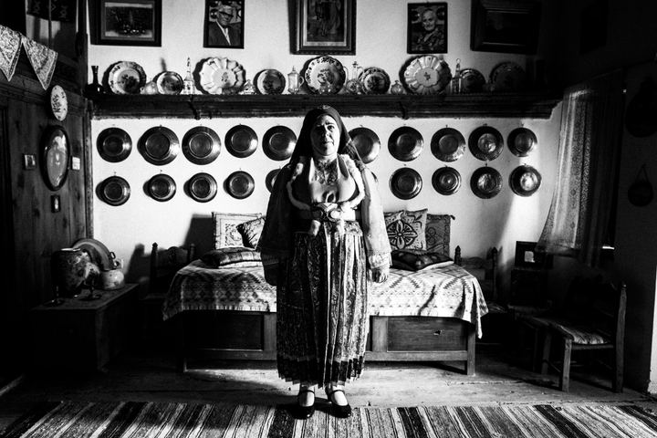A woman wearing the bridal dress of the island of Skyros, standing inside a local house
