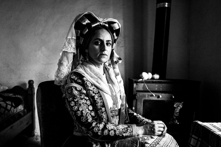 A woman wearing the costume of Southern Corfu posing inside a house in the village of Korakades.