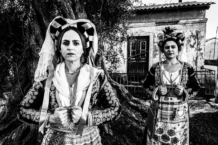 Two womenn wearing the costumes of Southern Corfu posing outside a house in the village of Korakades.