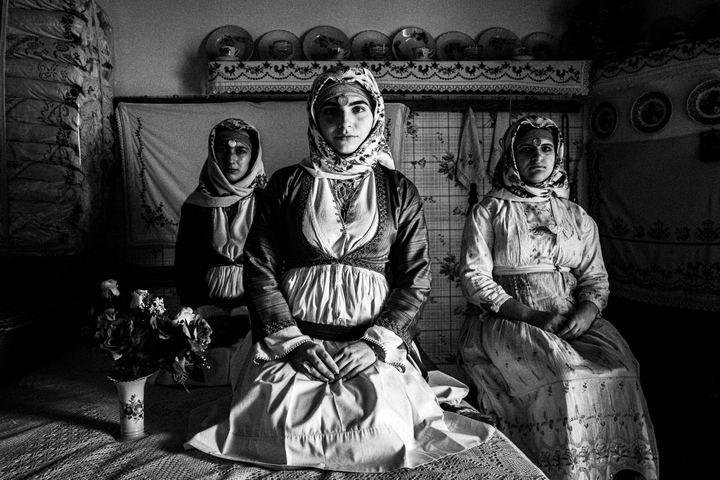 Three young women wearing the local dresses of Apollona, Rhodes, inside a local house