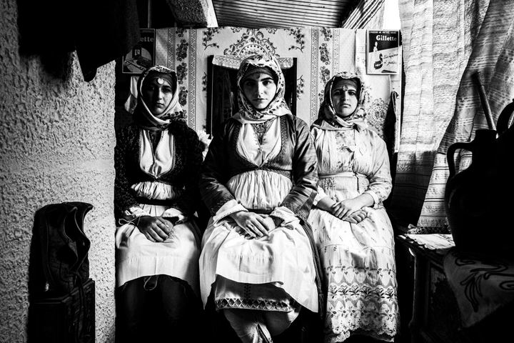 Three young women wearing the local dresses of Apollona, Rhodes, inside a local cafe