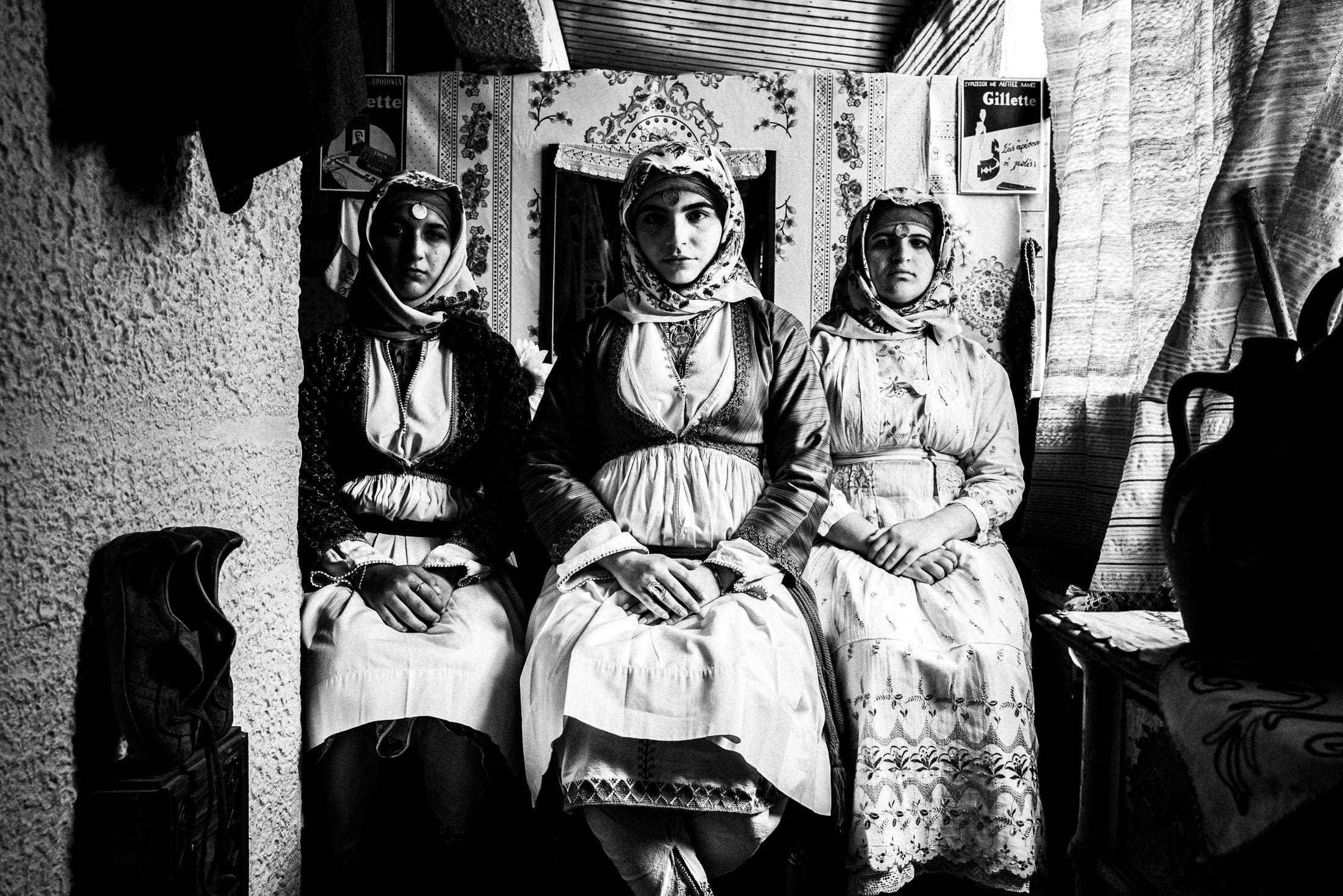 Three young women wearing the local dresses of Apollona, Rhodes, inside a local cafe