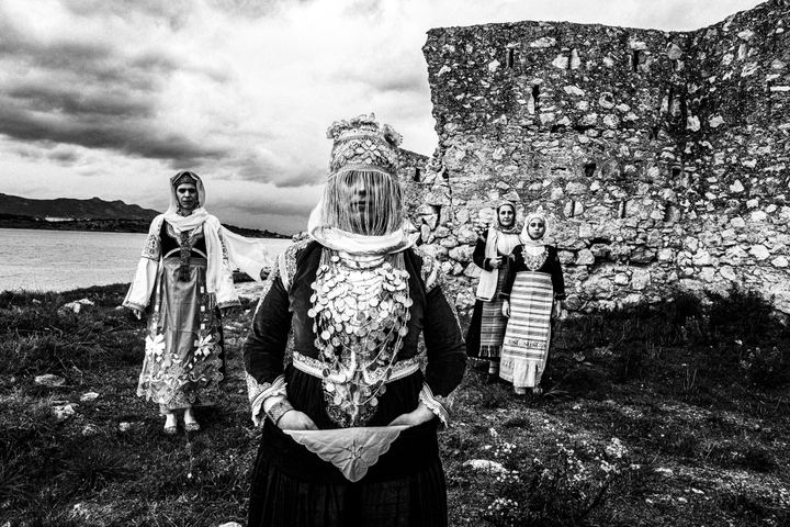 Four women wearing the costumes of Megara, Attica, standing in the fortifying walls of Agia Triada