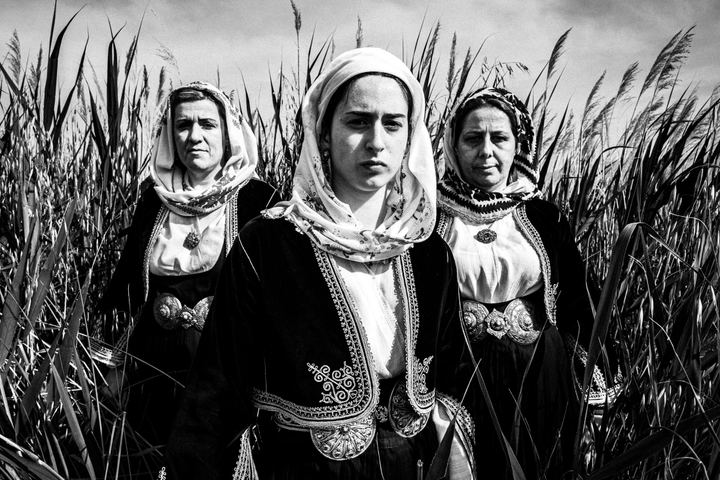 Women wearing the local costumes of Kymi in Euboea, standing in an arrow formation at a local field