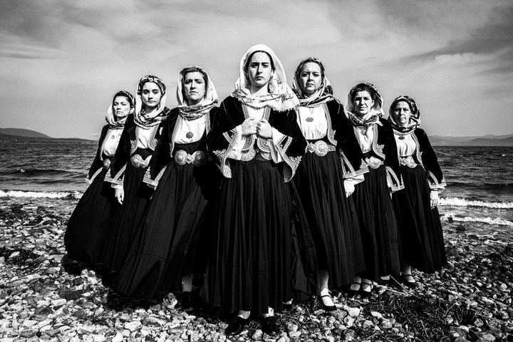 Women wearing the local costumes of Kymi in Euboea, standing in an arrow formation at a local beach