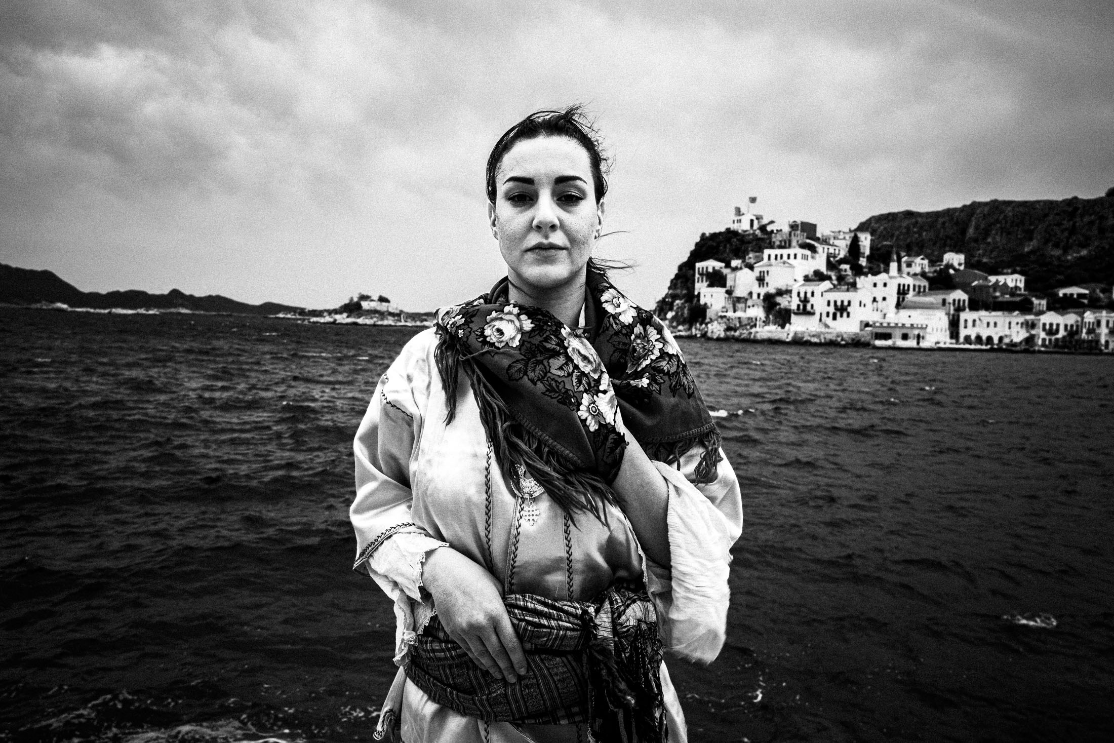 A woman wearing the local dress of Kastellorizo, standing before the sea on the island