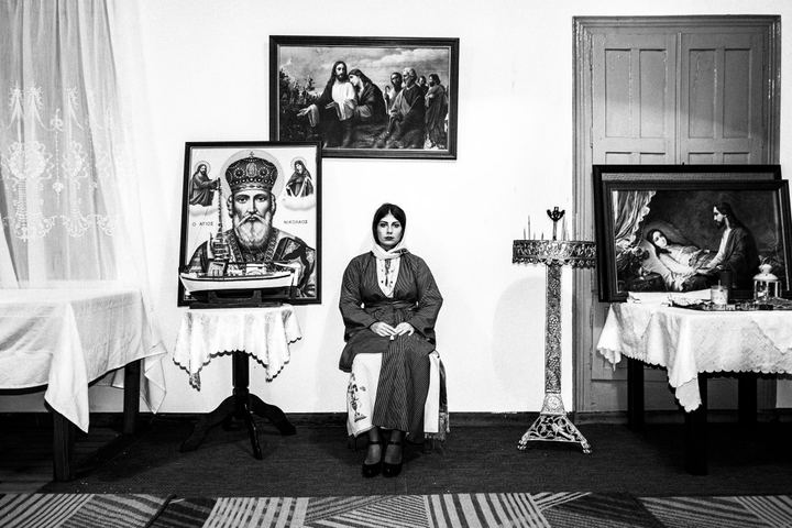 A woman dressed in the traditional costume of Kalymnos, sitting inside a local church.