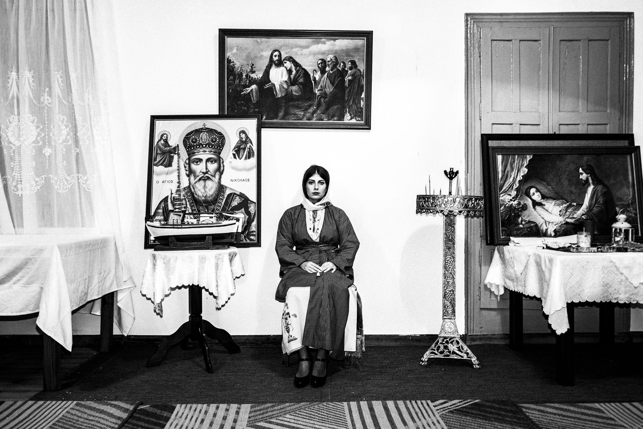 A woman dressed in the traditional costume of Kalymnos, sitting inside a local church.
