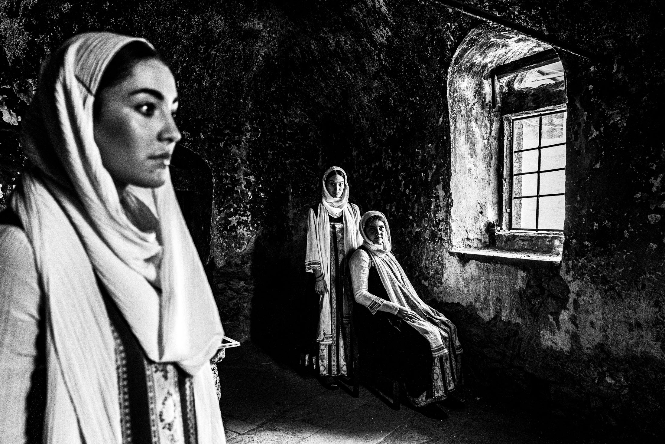 Women in the local dresses of Elata standing inside an old abandoned stone house