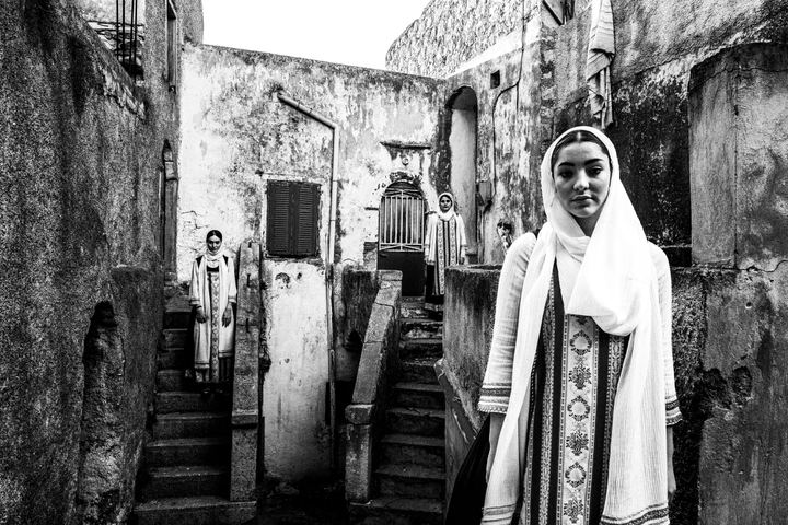 Three women wearing the local costumes of Elata standing at a local neighborhood