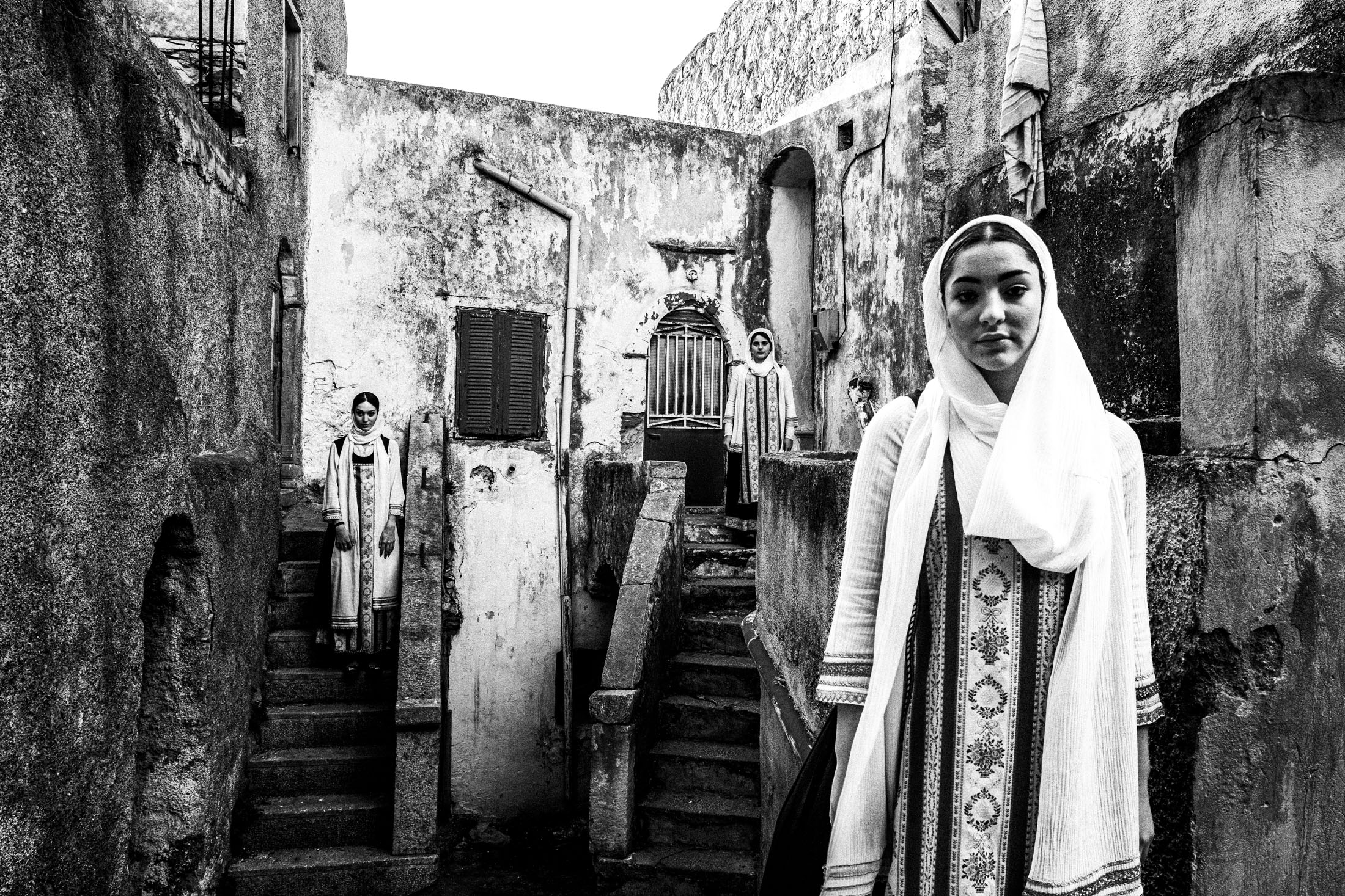 Three women wearing the local costumes of Elata standing at a local neighborhood