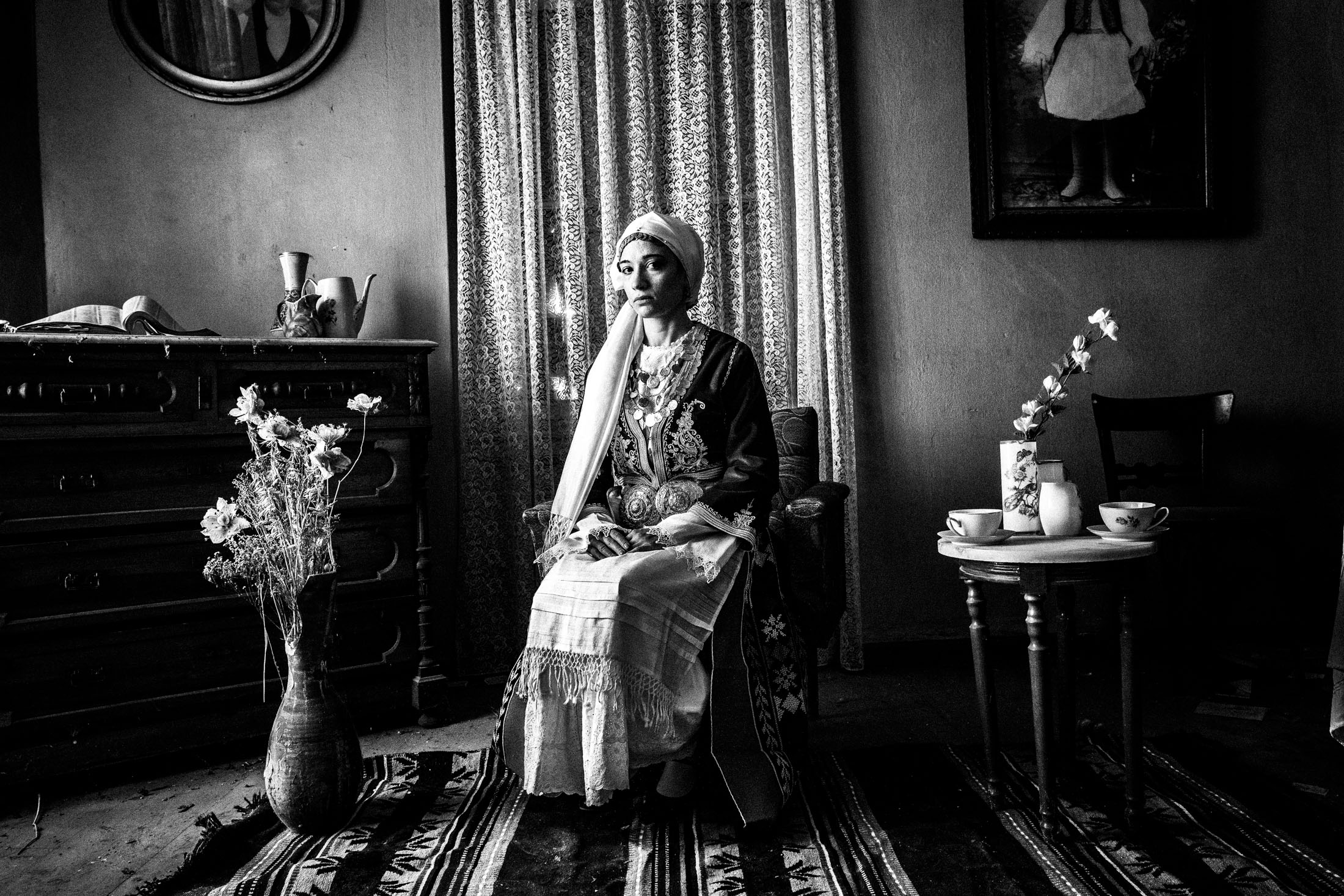 Woman wearing the local costume of Tegea in the Peloponnese, sitting on a wooden chair inside a local house