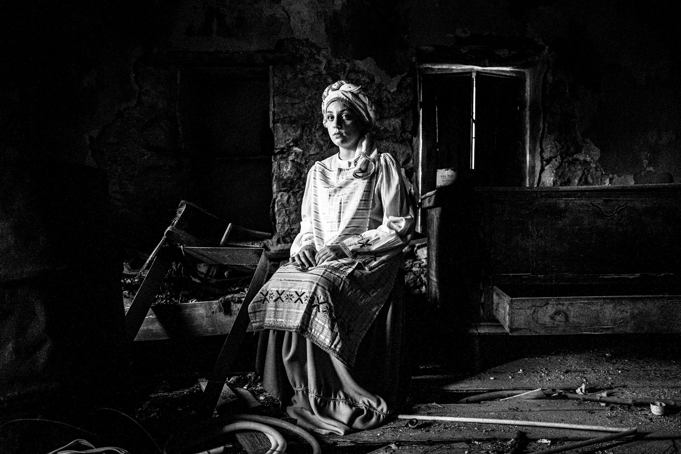 A young woman wearing the local costume of Dafnonas, sitting inside a local ruined house.