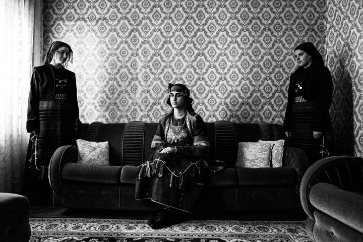 Three women in the local costumes of Drymos in Thessaloniki, inside a local house.