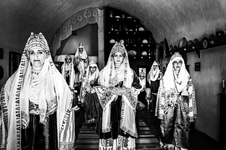 A group of women wearing the local bridal dresses of Astypalaea standing inside a local traditional house