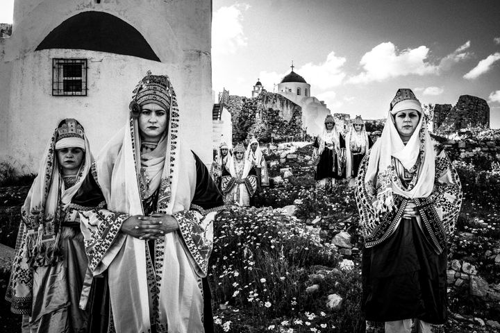 Women wearing the local bridal dresses of Astypalaea in Greece, standing inside the island's castle